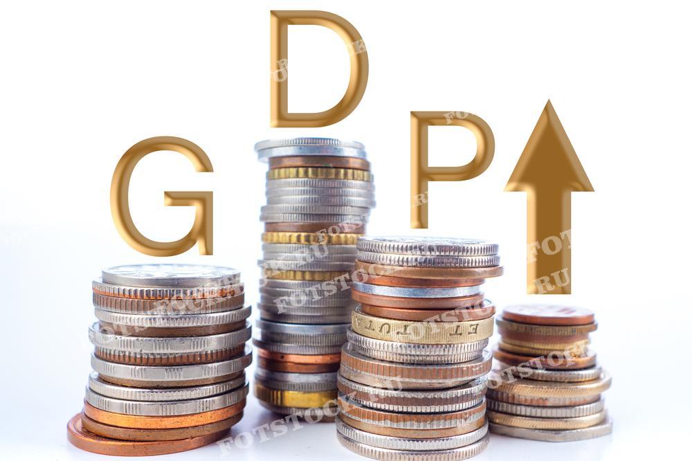 На фотографии изображены стопки монет различного номинала и аббревиатура GDP (валовой внутренний продукт) с направленной вверх стрелкой. Снимок символизирует рост экономики и увеличение валового внутреннего продукта.